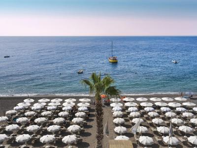 Beach with white umbrellas, blue sea, boats, serene and relaxing atmosphere.