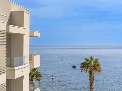 Vista mare con balconi e palme, atmosfera serena e rilassante.