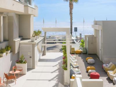 Terrazza moderna sul mare, arredi colorati e relax sotto il sole.