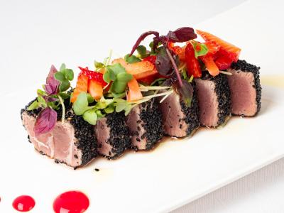 Tuna cubes with black sesame, topped with fresh, vibrant vegetables.