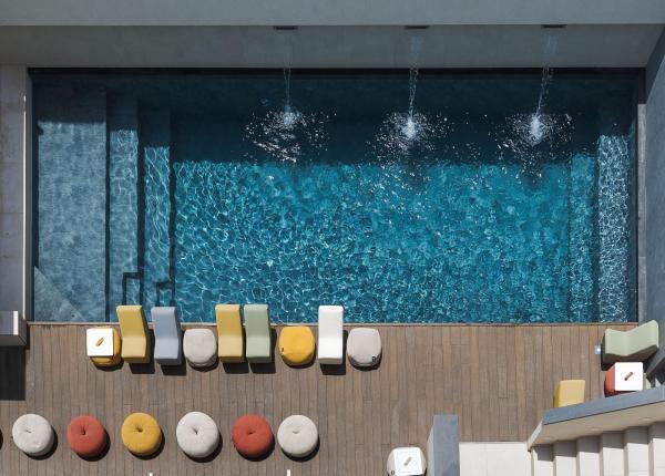 Piscina scintillante con sedie colorate, atmosfera rilassante e vivace.