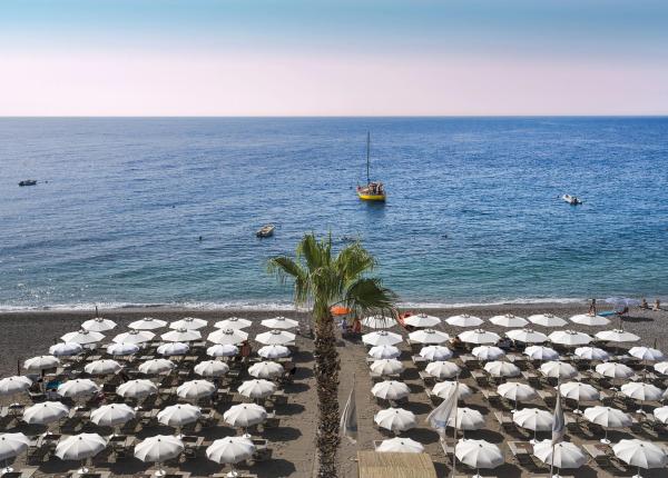 Beach with white umbrellas, blue sea, boats, serene and relaxing atmosphere.