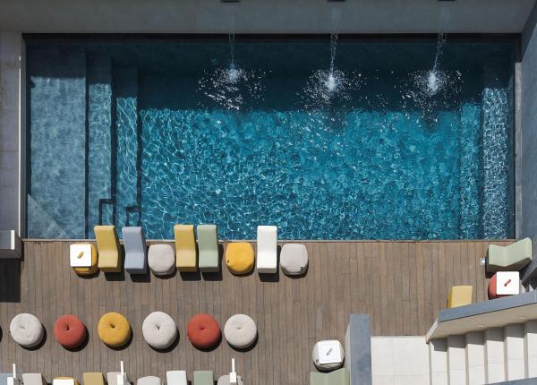 Piscina dall'alto, sedie colorate e atmosfera rilassante.