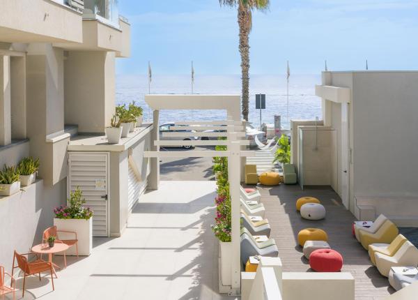 Terrazza moderna sul mare, arredi colorati e relax sotto il sole.