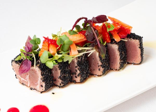 Tuna cubes with black sesame, topped with fresh, vibrant vegetables.
